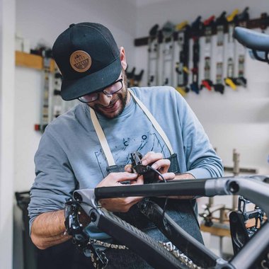Ein Mann repariert in der Werkstatt ein Fahrrad. 